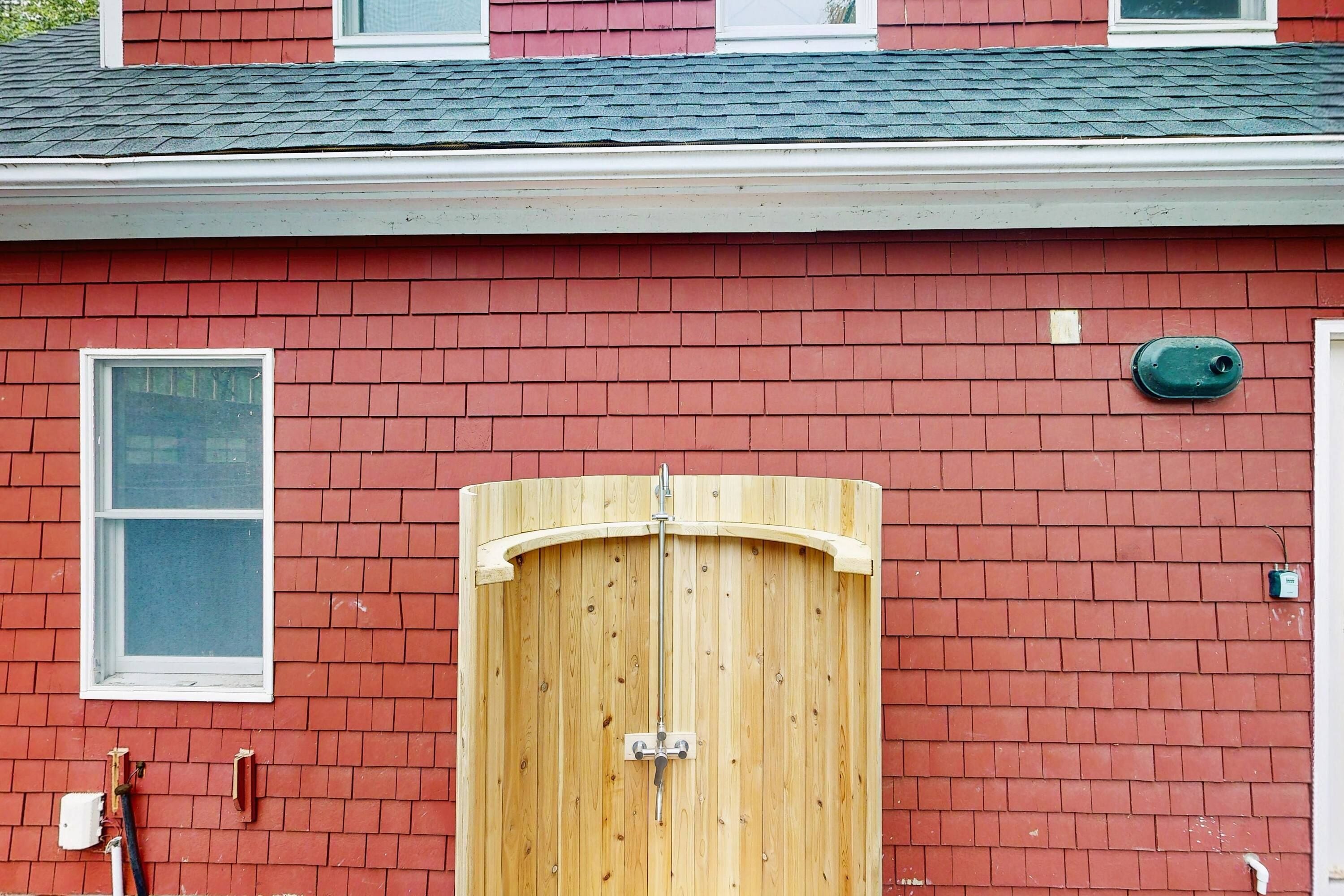 A red brick building with a wooden garage door, a window, and a green mailbox.