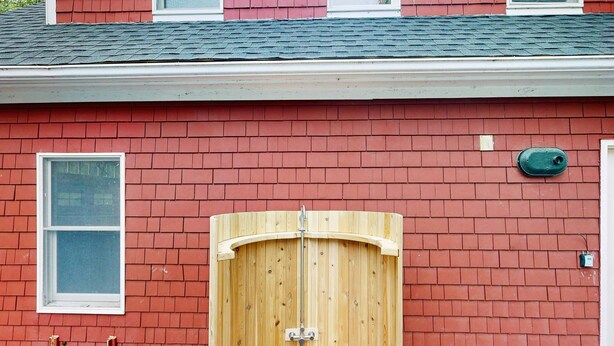 Een gebouw van rode baksteen met een houten garage deur, een raam en een groene brievenbus.