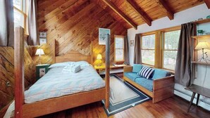 A wooden cabin interior with a bed, a sofa, and a desk. - Serene Home on 3 Acres w/ Wraparound Deck & Pool Table - Close to Beaches (Wellfleet)
