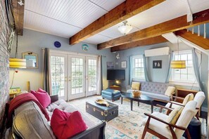 Ein gemütliches Wohnzimmer mit einer Couch, Sesseln, einem Couchtisch und einem Fernseher.
