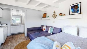 A modern room with a sofa, a bed, a kitchen area, and a framed artwork on the wall. - Cozy waterfront studio w/direct beach access - close to town (Truro)