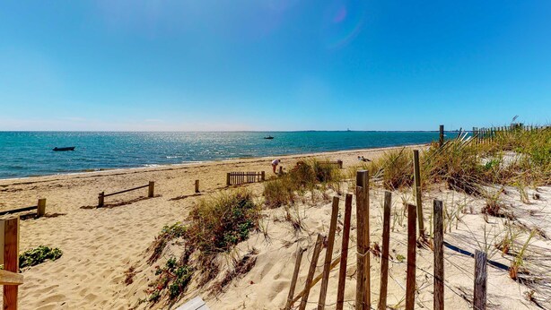 A beach with a wooden fence, sandy dunes, and the ocean. - Cozy waterfront studio w/direct beach access - close to town (Truro)