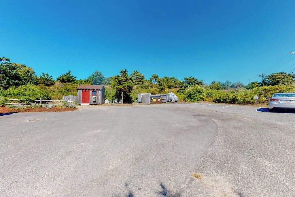 Um estacionamento com um pequeno edifício, uma área coberta e um carro.