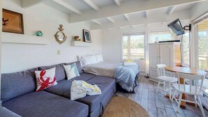 A cozy room with a sofa, a bed, a small table, and a TV. - Cozy waterfront studio w/direct beach access - close to town (Truro)