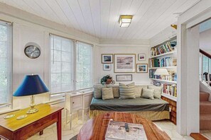 A cozy room with a bed, a desk, a bookshelf, and a clock on the wall.