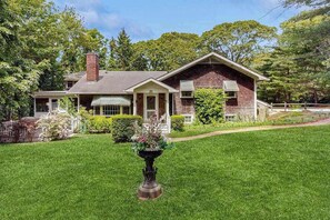 A two-story house with a front porch, a chimney, and a well-maintained lawn.