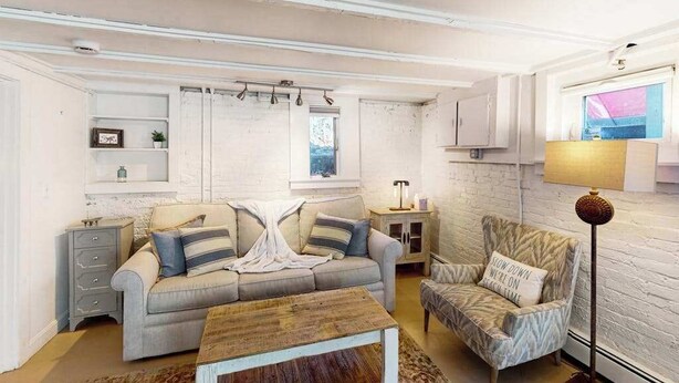 A living room with a sofa, armchair, coffee table, and a lamp. - Modern & bright condo with patio, W/D, and central location near town & beach (Provincetown)