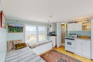A bedroom with a bed, a window, a view, a kitchenette, and a bathroom.