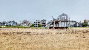 En ejendom ved stranden med flere huse, en sandstrand og en mole.