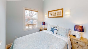 Quarto com cama, duas mesas de cabeceira, janela e luminárias fixadas na parede.