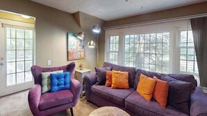 Una sala de estar con un sofá morado, una silla y una mesita.