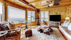 Un interno in legno con un televisore grande, una ventola a soffitto e vista dalle finestre.