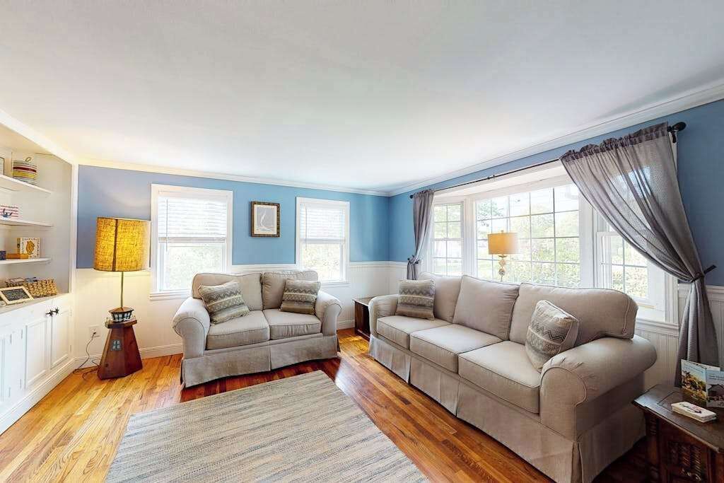 A living room with two sofas, a rug, a lamp, and a window with curtains.