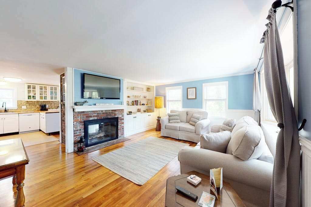 A living room with a fireplace, a sofa, a TV, and a kitchen area with cabinets and a countertop.