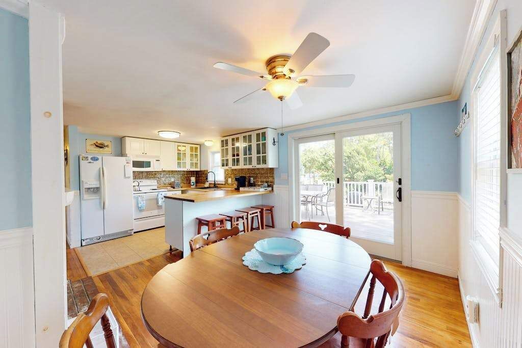 A kitchen with a dining area, a ceiling fan, and a view through a glass door.