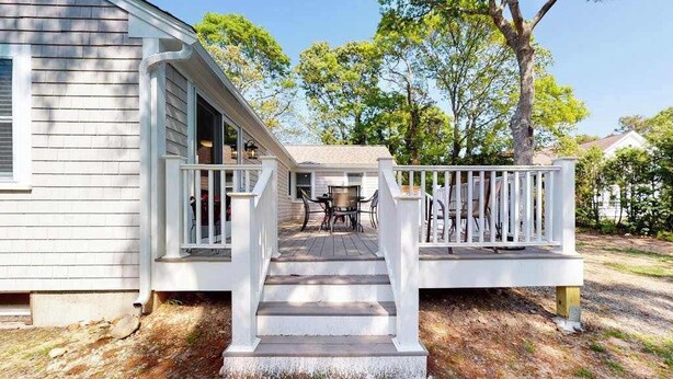 Ein Haus mit Veranda, Treppe und Tisch mit Stühlen.