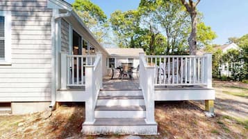 A house with a porch, steps, and a table and chairs.