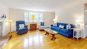 Ein Wohnzimmer mit einem blauen Sofa, einem blauen Sessel, einem Couchtisch aus Holz und einem gemusterten Sessel.