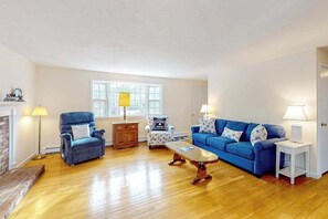 A living room with a blue sofa, a blue armchair, a wooden coffee table, and a patterned armchair. - Friendly retreat with a deck, AC, and board games - stellar central location (Chatham)
