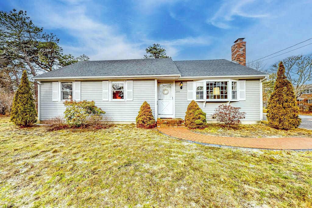 A single-story house with a front porch, a chimney, and a well-maintained lawn.