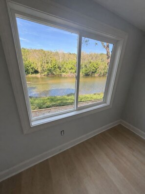 Una habitación con un ventanal grande que da a un lago y un bosque.