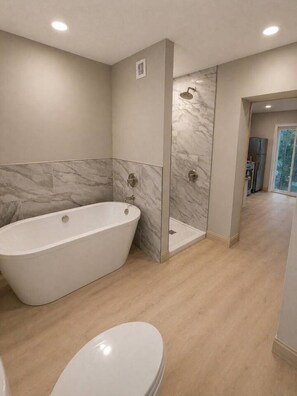 Un baño moderno con una bañera independiente, cabina de ducha y un inodoro.