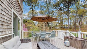 Een terras met buitenmeubilair, een tafel, stoelen en een parasol.