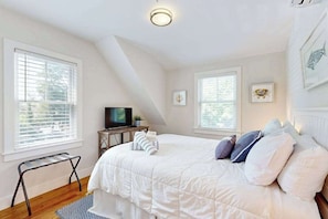 A bedroom with a bed, a TV, and a window. - New Lavish Condo in Heart of Downtown Chatham - Walk to Dining, Shops & Beach (Chatham)