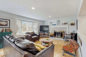 Ein Wohnzimmer mit einer Couch, Fernseher, Kamin und einem Gemälde an der Wand.