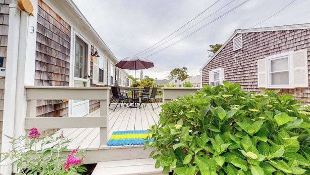 A wooden deck with outdoor furniture, a covered seating area, and a view of neighboring houses. - Family-friendly house w/gas grill, deck, streaming services - near Haigis Beach (Dennis Port)