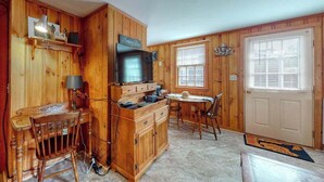 A wooden cabin interior with a kitchen, dining area, and a door with a window. - Family-friendly house w/gas grill, deck, streaming services - near Haigis Beach (Dennis Port)