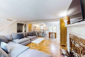 A modern living room with a sofa, coffee table, and fireplace. - Spacious Dennis Home with Large Deck & Backyard - Walk to Corporation Beach (Dennis)