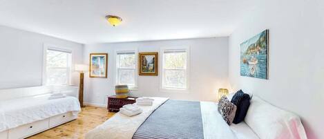 Un dormitorio con cama, mesita de noche, lámpara y ventana.