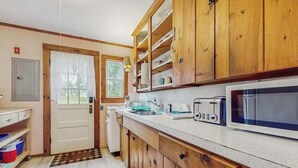 A kitchen with wooden cabinets, a microwave, a toaster, and a sink.
