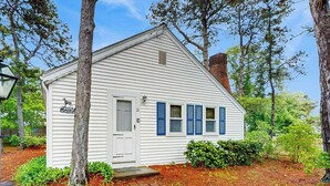 A small white building with blue shutters, a door, and a number '26' on the side.