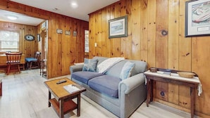 A wooden-paneled room with a sofa, a small table, and a framed picture on the wall.