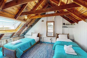 A room with two beds, wooden beams, a skylight, and a window. - Water-view home in great location with spacious backyard, grill, kayaks, dogs OK (Chilmark)