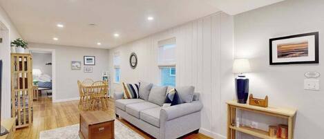 A living room with a sofa, wooden floor, a small table, and a bookshelf.