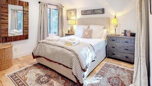 Een slaapkamer met een bed, twee bedlampen, een nachtkastje, een kaptafel, een spiegel en een vloerkleed.