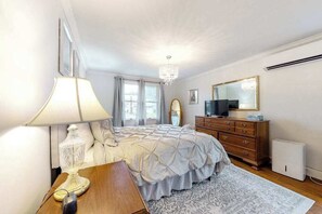 Ein Schlafzimmer mit Bett, Kommode, Spiegel, Lampe und Fernseher.