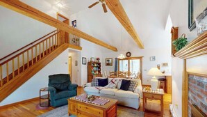 Un salon spacieux avec un escalier en bois, une cheminée et un coin salon confortable.