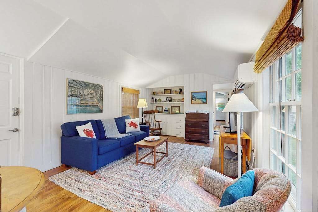 Uma sala de estar com um sofá azul, um tapete estampado e uma mesa de centro de madeira.