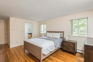 A bedroom with a wooden bed, a nightstand, a dresser, and a window. - Waterfront home with lovely lake views, great deck, sun porch & fireplace (Chatham)