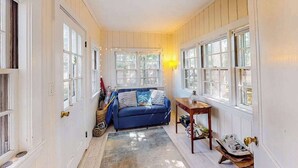 Ein schmaler Flur mit einem blauen Sofa, einem Holztisch und einer Lampe.