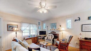 Ein Wohnzimmer mit einer Couch, Sesseln, einem Kamin und einem Fernseher.