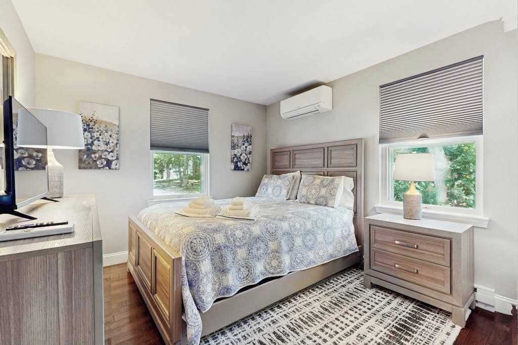 Un dormitorio con cama, mesitas de noche, escritorio y ventana con persianas.
