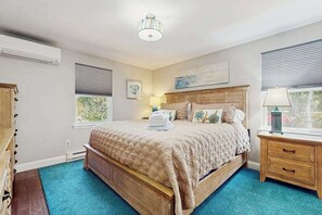 Ein Schlafzimmer mit Bett, Nachttisch, Lampe, Fenster und Deckenleuchte.