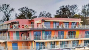 A multi-story hotel with balconies, a visible name sign, and a series of windows. - Largo Beach Hotel (Sunny Beach)