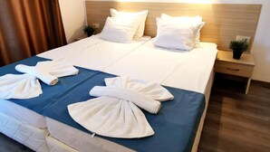 A hotel room with a bed, two bedside tables, a nightstand, and a potted plant. - Largo Beach Hotel (Sunny Beach)