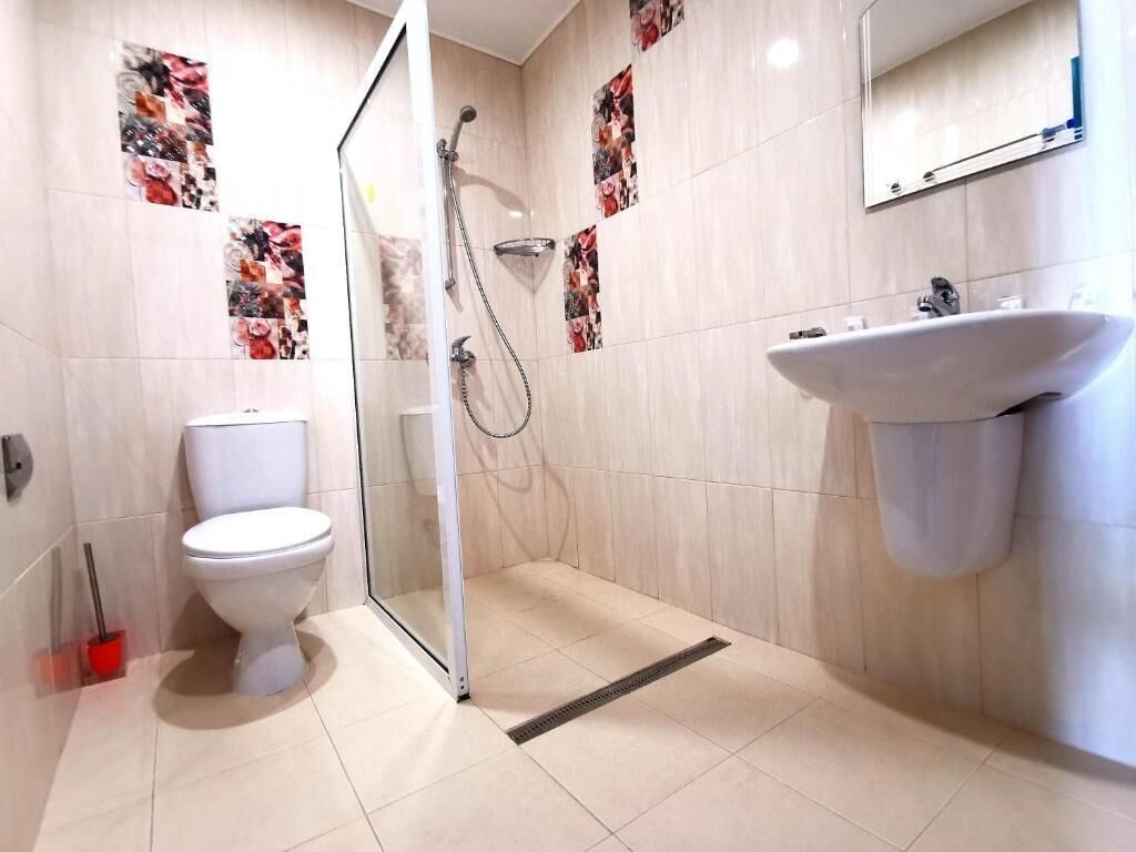 A bathroom with a toilet, shower, and sink.